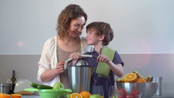 Young Caucasian Mother And Child Homemade Fresh Orange Juice In Kitchen With Electric Juicer