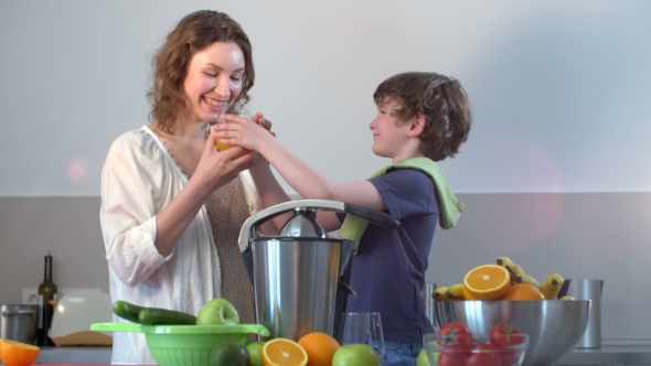 Young Caucasian Mother And Child Homemade Fresh Orange Juice And Drink It