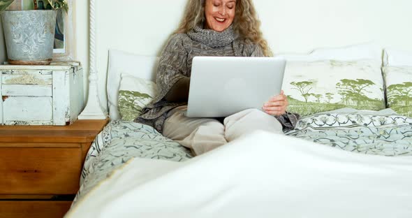 Mature woman using laptop in bedroom 4k