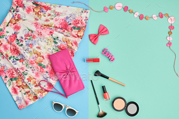  essentials. Cosmetics, makeup. Stylish pink handbag clutch, trendy dress, necklace, sunglasses . Unusual overhead outfit, top view on blue