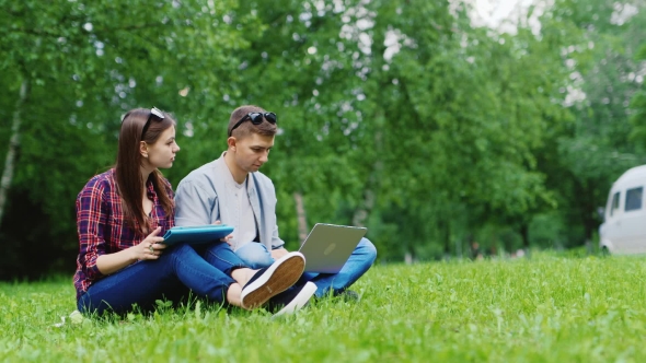 College Students Studying Together In Nature. Enjoy Your Tablet And Laptop