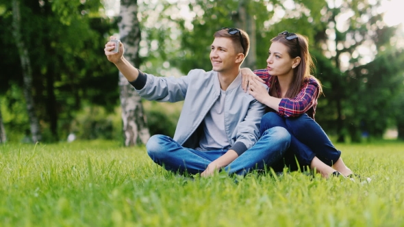Young Couple Resting In a Park, Makes Selfie
