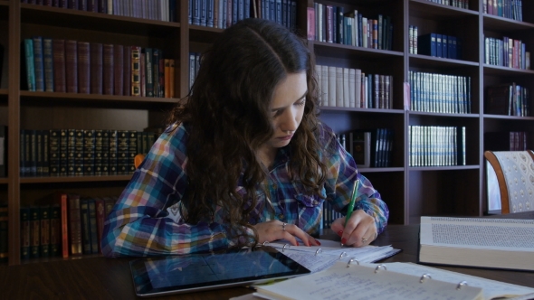 A Student Sits In The Library And Preparing For University Exams. 