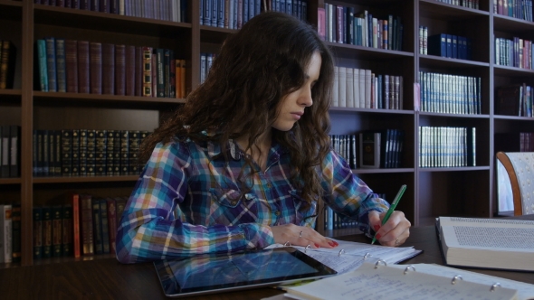 A Student Sits In The Library And Preparing For University Exams. 