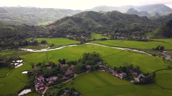 Picturesque Aerial View of Green Paddy Fileds with Small Village and Hills