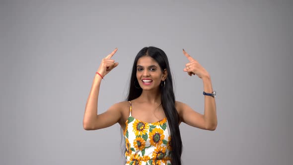 Happy and excited Indian girl pointing upwards for ad, product placement,  banner, etc