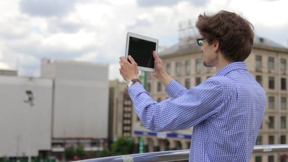 The Young Man Makes for Panoramic View Photos Using the Tablet