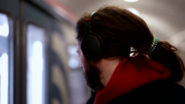 Portrait of a Cute Young Man with Headphones Listening to Music at a Metro Station Waiting and