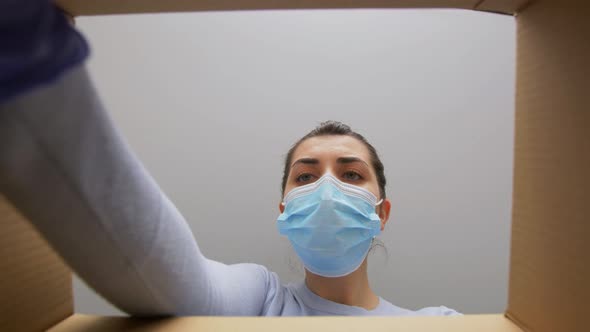 Woman in Mask Opening Parcel Box with Medicine