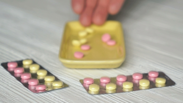 Hand Folds Tablets In Container Placed On a Table