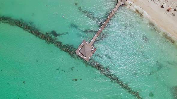 Beautiful aerial view of dock above the peaceful greenish sea on sunny day.