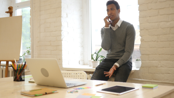 Creative Black Designer Talking on Phone at Workplace