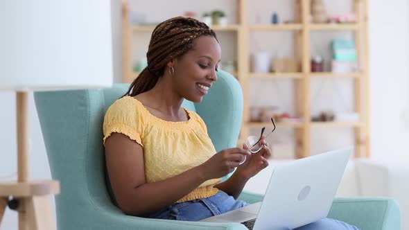 Beautiful African American Woman is Using Laptop While Sitting in Chair at Home Room Spbi