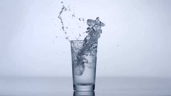 Slo-motion ice cubes falling into glass