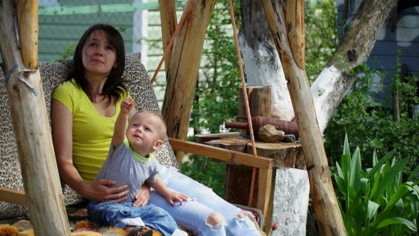 Pretty Young Mother With a Young Son Ride On a Swing