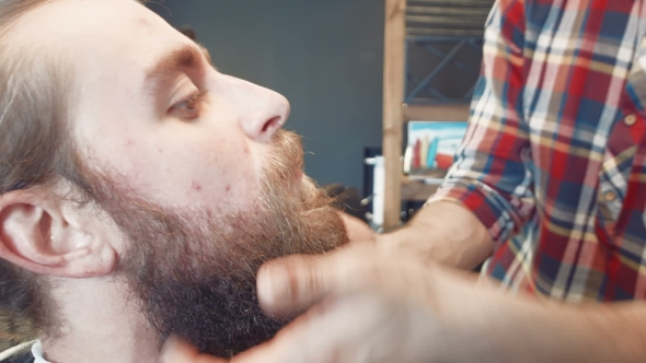 Barber Spreading Oil On Man's Beard