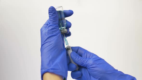 Health Worker Dials the Vaccine From Ampoule Into a Syringe Wearing Blue Protective Gloves