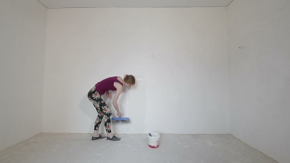 Young Girl Plastering Wall With Trowel In Her Home