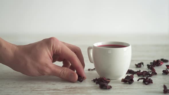 White Cup With Warm Red Hibiscus Tea On Wooden. Dried Hibiscus Sudanese Rose Flowers, Hibiscus