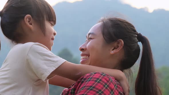 Happy little daughter hugs and kisses her mother in the park. family relationship concept