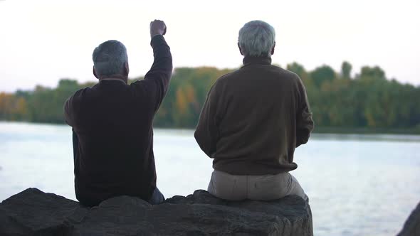 Elderly Pensioners Throwing Stones in Water, Sitting on River Bank, Weekend Rest