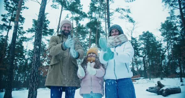 Father Mother and Daughter Smile Shaking Snow Off Gloves