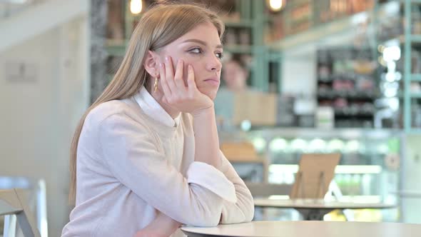 Pensive Young Woman Thinking in Cafe