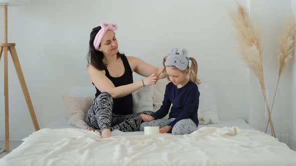Woman Combing Hair of Daughter in Modern Bedroom