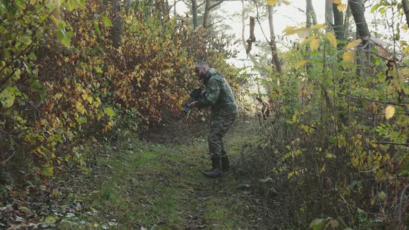 Soldier Looking for a Trace of the Enemy with a Rifle in a Forest