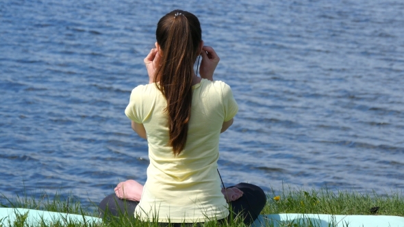 Young Woman Meditating And Listening Music In Headphones In Lotus Position