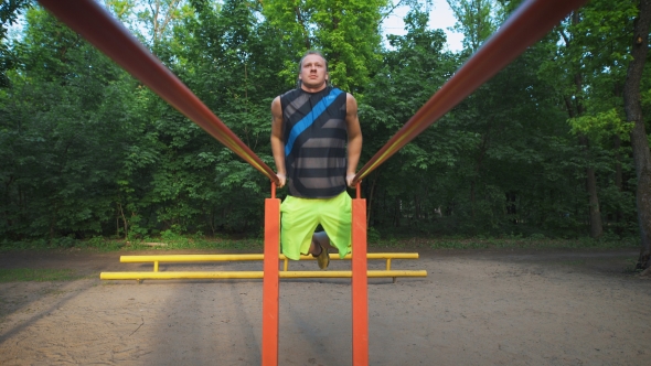 Muscular Man During His Workout In Park. Dips, Exercise Chest And Triceps.