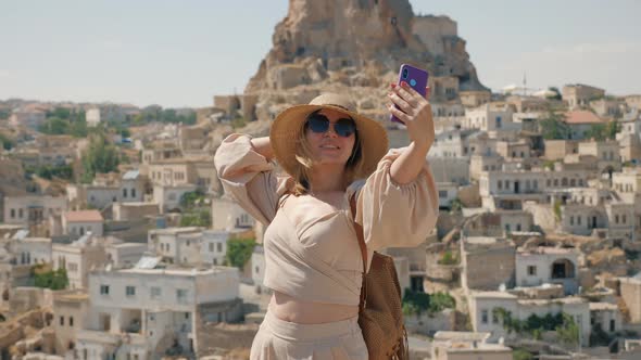 A Woman Takes a Selfie on the Background of the City with the Ortahisar Fortress