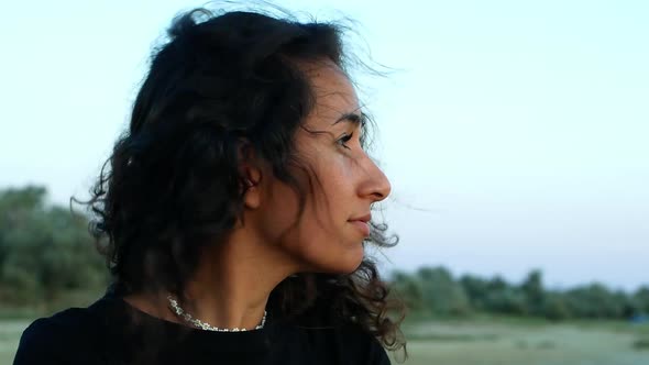 A beautiful mixed-race woman in nature looks around and enjoys the beautiful sunset.