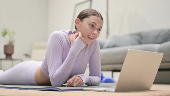 Young Latin Woman Talking on Video Call on Laptop on Yoga Mat