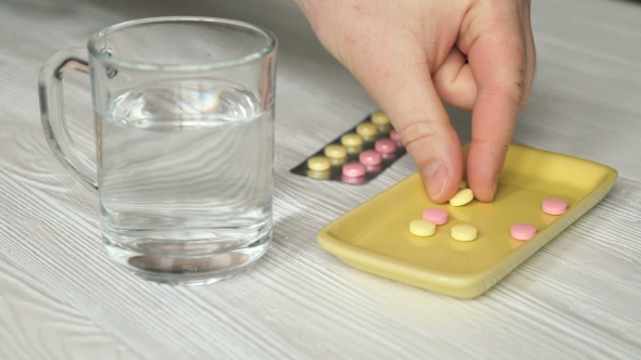 Man's Hand Takes The Tablets From The Container