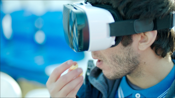 Guy Eating Popcorn In VR Glasses On Tribune