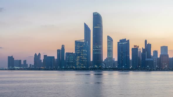 Abu Dhabi City Skyline with Skyscrapers Before Sunrise with Water Reflection Night to Day Timelapse