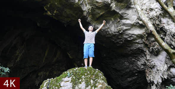 Man Celebrating On The Top Of Rock, In Front Of Cave