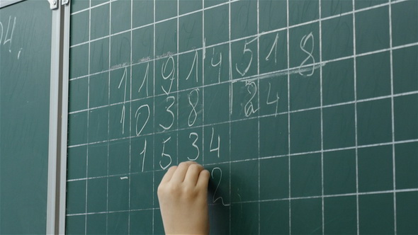 A Little Boy Solves Math on the Chalkboard at Primary School