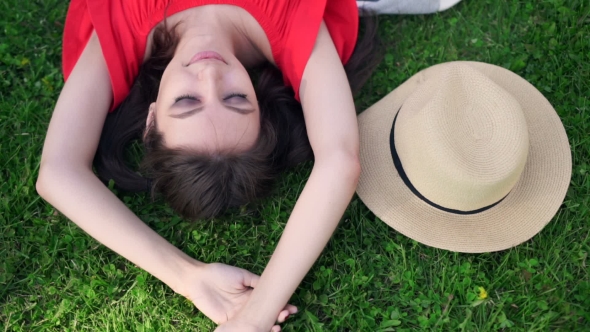 Relaxing In Grass. Top View Of Beautiful Young Woman On The Green Grass