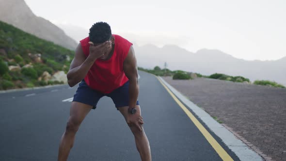 Tired african american man taking a break from running on the road