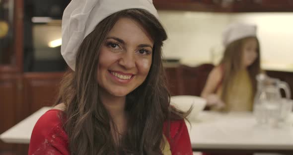 Close-up Portrait of Young Caucasian Woman in Cook Hat Looking at Camera and Smiling. Beautiful