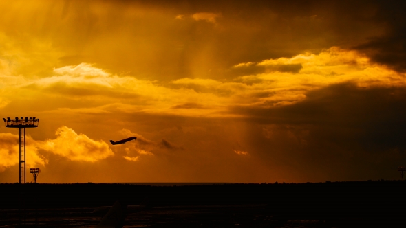 Passenger Plane Fly Up Over Take-Off Runway From Airport At Sunset