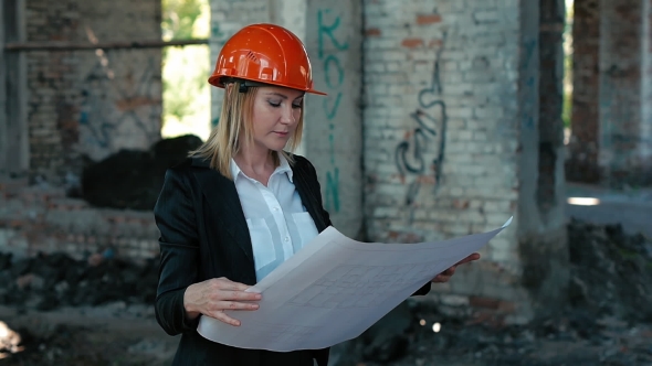 Engineer in Helmet Holding Building Plan in Hand