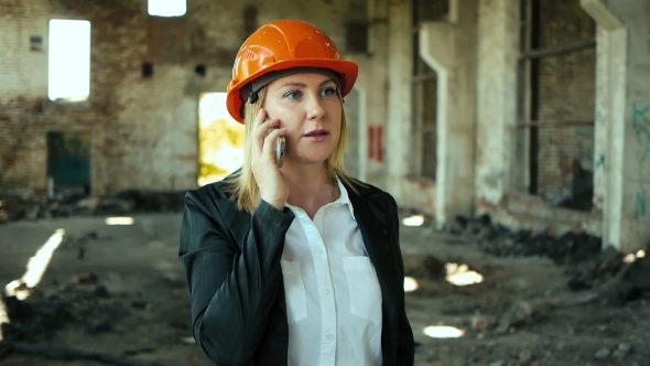 Engineer in a helmet speaks on the phone at the construction site