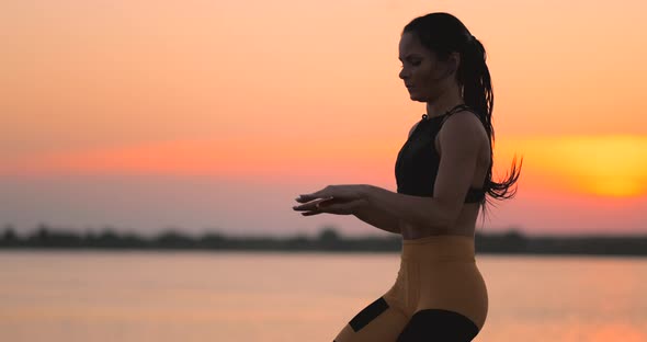 Woman Trains Running on the Spot at Sunset on the Beach Near the Pond