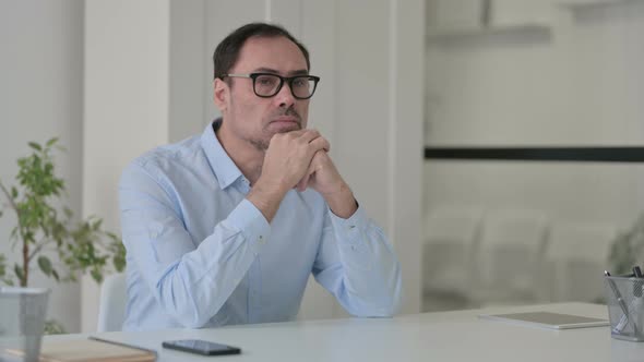 Pensive Middle Aged Man Thinking While Sitting in Office