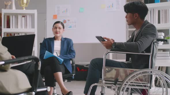 Confident business man in wheelchair presenting during business meeting with colleagues.