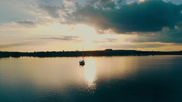 Aerial View One Yacht at Sunset Near the Barge. Flight at Sunset Near the Yacht with a Sail. The Sun