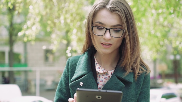 Portrait Of The Girl Using a Tablet And Touching Hair Outdoor 